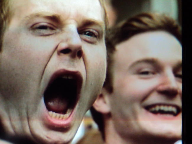photo of a yawning man in the background of a politician's speech on TV