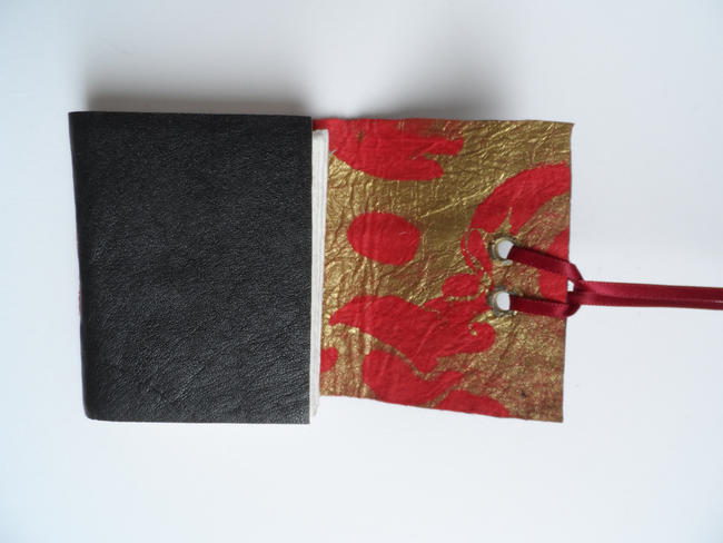 Leather cover lined with red and gold paper, ribbon closure