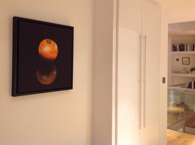 'Orange' in black floating frame in hallway