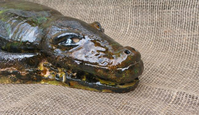 Detail of a clay sculpture of an alligator.