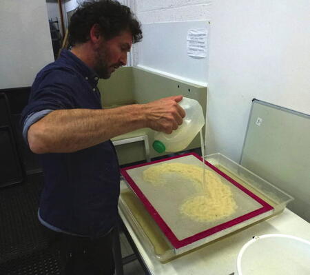 Pouring out the pulp to make a paper cloud on the mesh screen. paper Studio Northumbria, Northumbria University