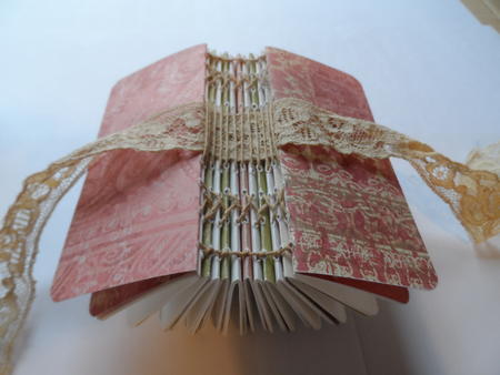 Exposed stitched spine with lace ribbon close.