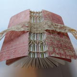 Exposed stitched spine with lace ribbon close.