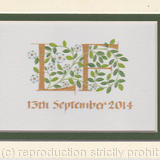 Two letters in gold with white roses and green leaves